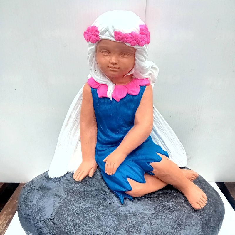 Seated fairy in a blue dress with a pink flower crown, perched on a grey rock